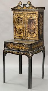 Chinese lacquered secretary in three parts, top molding over upper portion with large finial and two doors over desk with hinged wri...