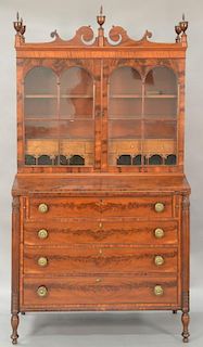 Sheraton mahogany secretary desk in three parts, upper section with carved pediments and five urn finials on mid section having glaz...