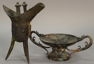 Two Archaic bronze vessels including a wine vessel with three sabre style legs and an elongated spout (ht. 7 1/2in.) and the other w...