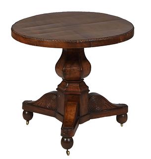 French Empire Carved Walnut Center Table, 19th c., the beaded rim circular top over a wide skirt on a four sided baluster urn support, to large tripod