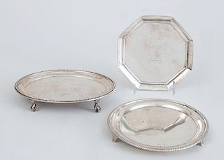TWO GEORGE III SILVER TEAPOT STANDS AND A GEORGE III CRESTED OCTAGONAL SMALL TRAY