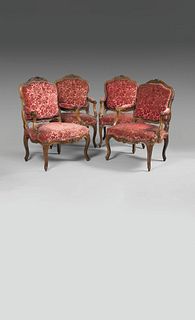 SET OF FOUR FLOWER-CARVED FLAT-BACKED ARMCHAIRS in walnut.