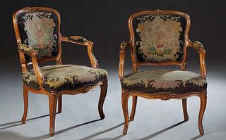 Pair of French Carved Beech Louis XV Style Fauteuils, early 20th c., the canted floral carved upholstered back to upholstered arms, above a bowed seat