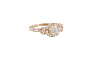 Lady's 18K Rose Gold Dinner Ring, with a central .5 carat round diamond, atop a border of tiny round diamonds, flanked by diamond mounted lugs and sho