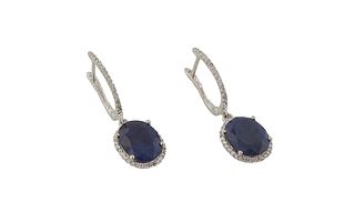 Pair of 14K White Gold Pendant Earrings, the half hoop diamond mounted studs suspending a 3.98 ct. oval blue sapphire atop a border of tiny round diam