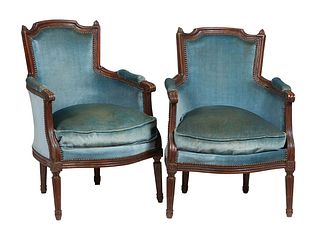 Pair of French Louis XVI Style Carved Beech Fauteuils, early 20th c., the curved arched upholstered highback over upholstered scrolled arms and a bowe