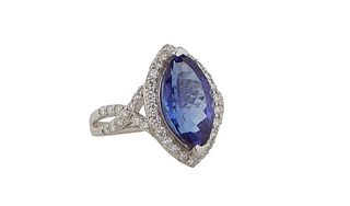 Lady's Platinum Dinner Ring, with a 6.85 carat marquise tanzanite atop a conforming border of round diamonds, the split shoulders of the band also mou