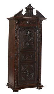 French Renaissance Style Carved Oak Bonnetiere, 19th c., the peaked broken arch crest with a shield and sword relief carving over a break front crown 