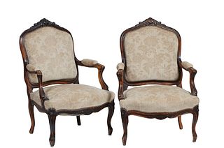 Pair of French Carved Walnut Louis XV Style Fauteuils, 19th c., the arched canted shield shaped back with scroll and floral carving, over upholstered 