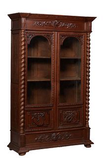 French Provincial Henri II Carved Oak Bookcase, c. 1880, the stepped breakfront crown over setback carved frieze above setback arched glazed doors wit