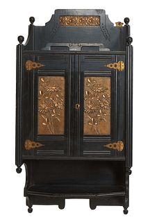 English Aesthetic Ebonized Wood and Brass Wall Cabinet, c. 1880, the finialed back splash with a relief brass floral plate, over a double door cupboar