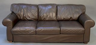 Brown leather sofa with three cushions.