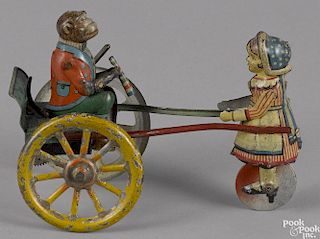 Gama tin lithograph lever action monkey in a cart toy, being pulled by a young girl