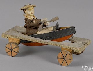 Painted pine and composition articulated boy in a row boat pull toy, probably German, 8'' l.
