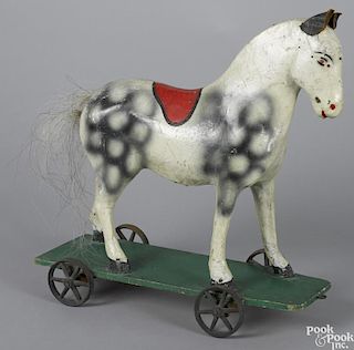 Composition platform horse pull toy, with a dappled surface and iron wheels, 18'' h., 17 1/2'' l.