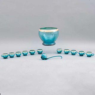 PONCHERA. ITALIA, SXX. Elaborada en cristal color azul, con esmalte dorado. Consta de: 11 tazas, cucharón y ponchera.  25 cm