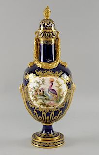 Continental porcelain urn with blue ground and gilt swags decorated with vignettes of exotic birds.