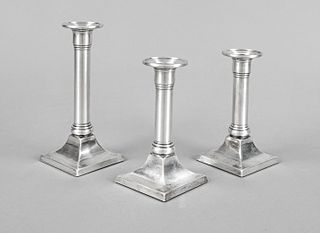 Three candlesticks, USA, 20th century, sterling silver 925/000, curved and filled square stand, columnar shaft merging into the spout, h. 14,5 and 17,
