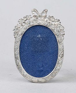 Small oval photo frame, German, 20th century, silver 800/000, frame with relief decoration and bow crowning, clear measure 8 x 6 cm, total measure 11,