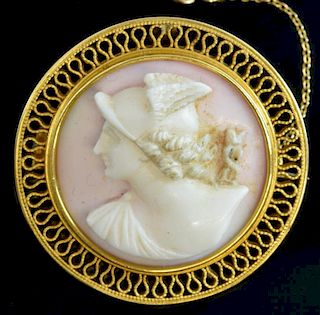 A carved pink shell cameo brooch depicting the profile of Mercury within a gold wire border mounted in unmarked yellow metal.
