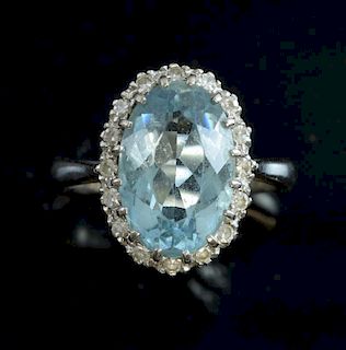 Aquamarine and diamond cluster, oval-cut aquamarine to the centre with a surround of diamonds mounted in 18 ct white gold.