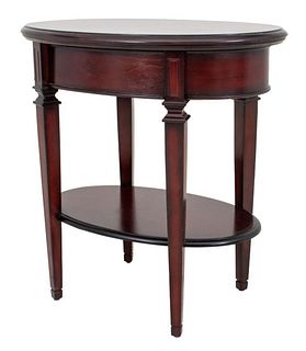 Directoire style mahogany side table having oval top with one drawer above fluted square tapered legs jointed by one shelf. 26" H x 25.5" W x 17.25