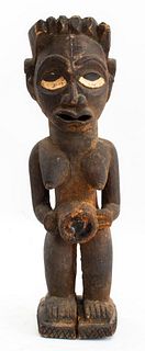 African tokoloshe figure, Zulu people, Kwa-Zulu, South Africa, depicting a woman, the figure holding a glass-inset disc. 17.5" H x 5.5" W x 5" D.