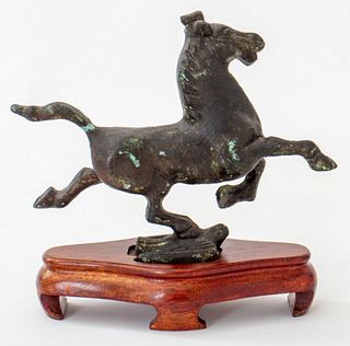 Chinese patinated metal sculpture depicting a galloping horse standing on a bird, raised on a wooden stand, apparently unsigned. Without base: 5.5" H 