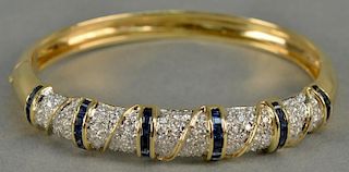 Hinged sapphire and diamond bangle bracelet in 18K (stamped) yellow gold. The bracelet centers two rows of fourteen channel s
