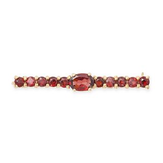 A VINTAGE GARNET BAR BROOCH in 9ct yellow gold, comprising a central oval cut garnet and rows of ...