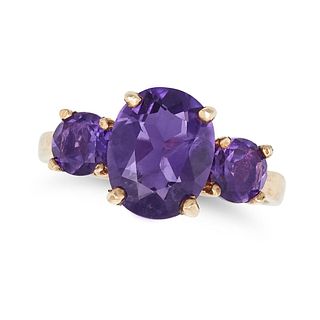AN AMETHYST THREE STONE RING in 9ct yellow gold, set with an oval cut amethyst between two round ...