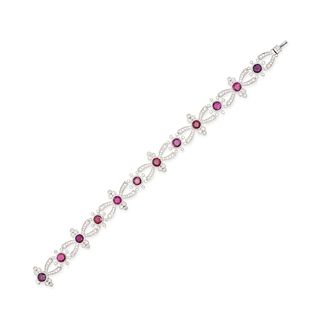 A RUBY AND DIAMOND BRACELET in platinum, the openwork links set with a row of twelve round cut ru...