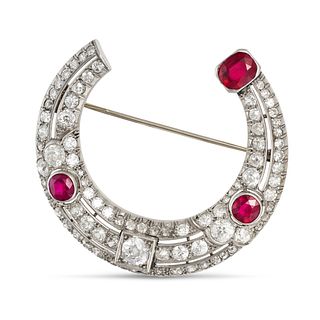 A RUBY AND DIAMOND HORSESHOE BROOCH, 1940s in platinum and 18ct white gold, designed as an openwo...
