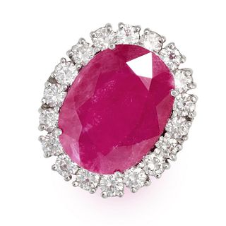 A RUBY AND DIAMOND CLUSTER RING in platinum, set with an oval cut ruby of 11.03 carats in a clust...