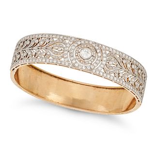 AN ANTIQUE DIAMOND BRACELET in 18ct yellow gold, the open work hinged bangle in foliate design se...
