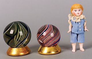 Two large marbles, together with a bisque doll.