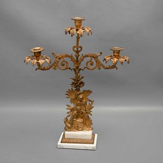 CANDELABRO. SXX. Bronce dorado, para 3 luces; decorado con relieves de figuras vegetales y escena campirana; bases de alabastro. 50 cm.