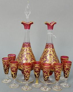 Cranberry cut to clear glass eleven piece decanter set having etched cranberry body with gilt leaf decoration including two c