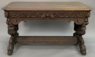 Victorian carved oak writing table having shaped carved top on scroll carved freize with lion corners, set on double supports
