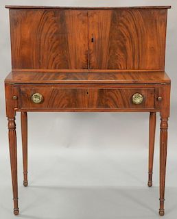 Sheraton mahogany desk with doors over flip lid writing surface over one drawer set on turned and fluted legs, circa 1830. 
h