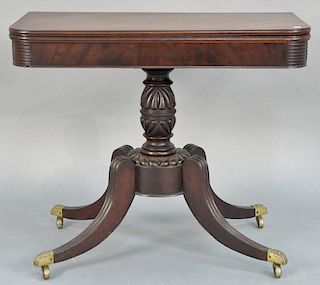 Mahogany Duncan Phyfe school games table having rectangular top on turned and carved pedestal set on four downswept members, 