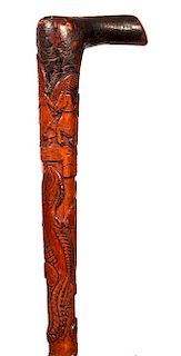 96. Great American Folk Cane- Ca. 1870- A one piece carved hardwood cane with various high relief carvings which include ange