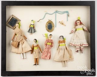 Framed group of small dolls and accessories