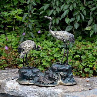 A bronze polychromed sculptural group of two red-crowned cranes, one with head lifted, the other with head down, on rockwork