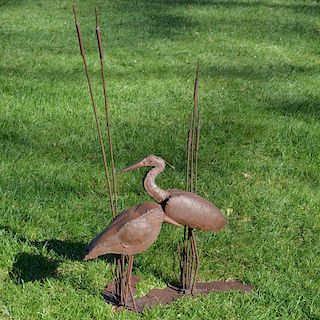 A wrought-iron sculptural group of two shorebirds, a sandpiper and heron, standing among cattails