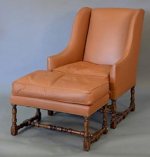 Tan leather Jacobean style wing chair with matching ottoman (slight wear to arms).