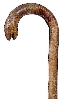 234. Snakeskin Hiking Cane - Ca. 1930 – A completely covered wood shaft with an exotic snakeskin and an open mouth, the hea