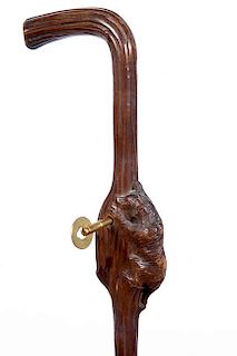 148. Music Box Cane- Late 19th Century- A Black Forrest carved bear with a large red glass eye, working  music box with key,