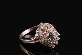 A gold floral cluster ring with a sapphire center and Zirconia accents.
