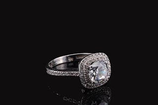 A white gold ring with a round central Zircon surrounded by a halo of smaller Zircons on a pavé band